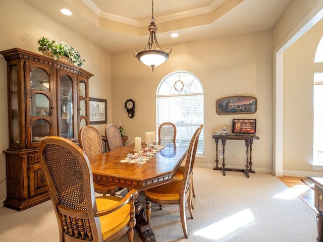 carpeted dining space featuring crown molding and a tray ceiling