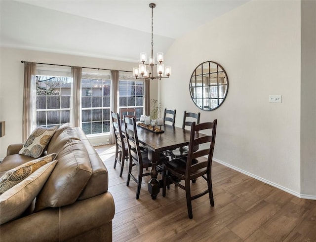 dining area with hardwood / wood-style flooring, vaulted ceiling, and a notable chandelier