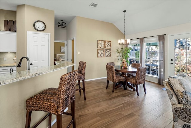 dining space featuring lofted ceiling, sink, dark hardwood / wood-style floors, and an inviting chandelier