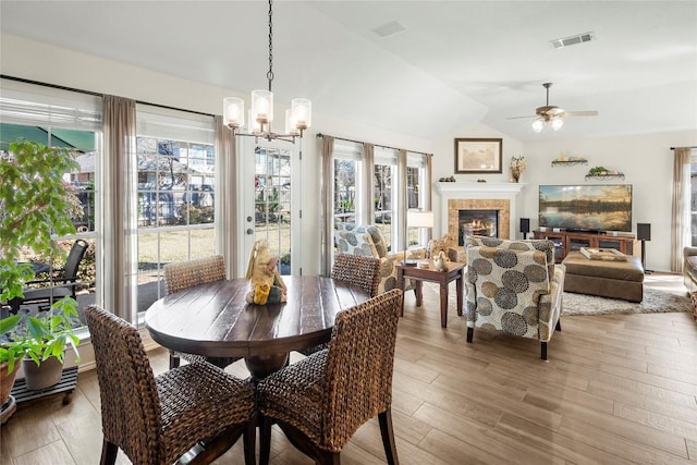 dining space with lofted ceiling, ceiling fan with notable chandelier, and light hardwood / wood-style flooring