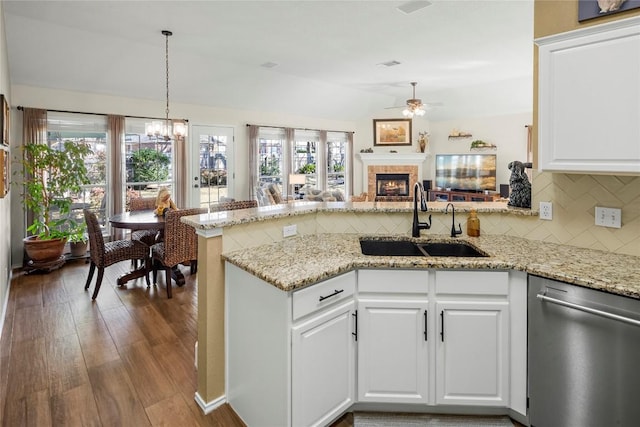 kitchen featuring sink, hanging light fixtures, white cabinets, stainless steel dishwasher, and kitchen peninsula