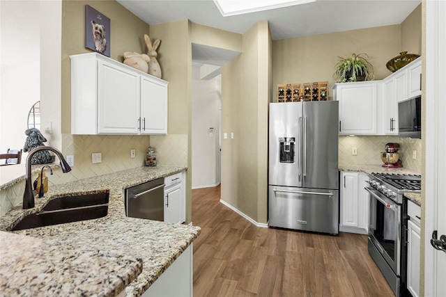 kitchen featuring light stone counters, appliances with stainless steel finishes, sink, and white cabinets