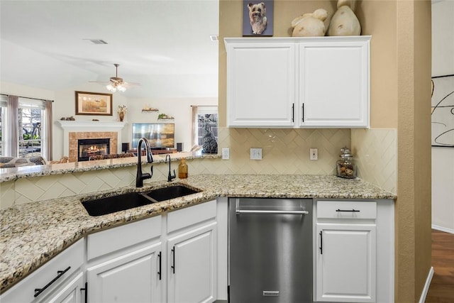 kitchen with sink, light stone countertops, white cabinets, decorative backsplash, and stainless steel dishwasher