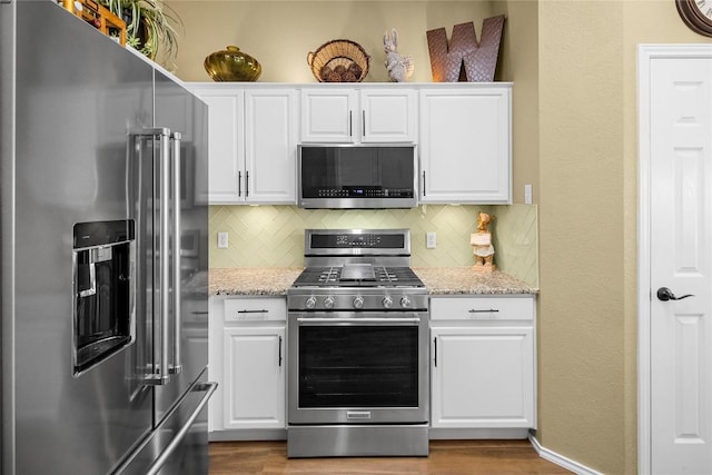 kitchen with appliances with stainless steel finishes, light stone countertops, and white cabinets