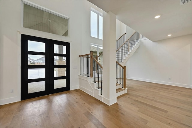 foyer featuring french doors, wood-type flooring, and a high ceiling