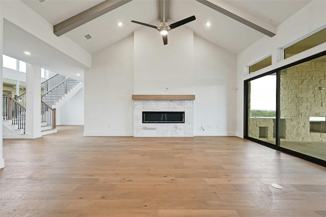 unfurnished living room featuring beam ceiling, light wood-type flooring, and a fireplace