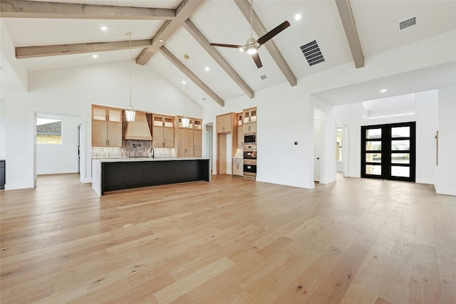 unfurnished living room with light hardwood / wood-style floors, high vaulted ceiling, french doors, and a healthy amount of sunlight