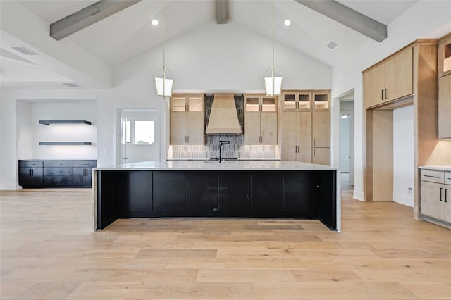 kitchen with sink, premium range hood, hanging light fixtures, a large island with sink, and light brown cabinets