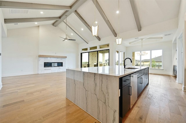 kitchen with a large island, hanging light fixtures, light stone countertops, and sink