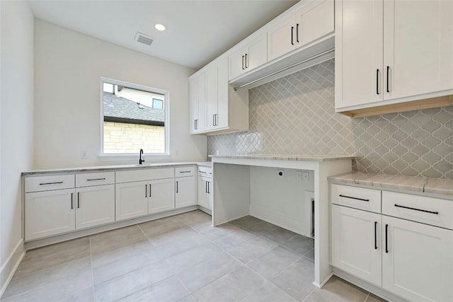 kitchen featuring white cabinetry, light tile patterned flooring, sink, and decorative backsplash