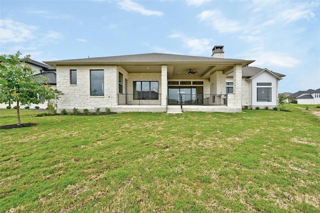 rear view of house with ceiling fan and a yard