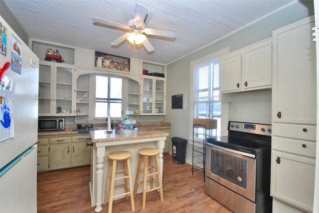 kitchen with plenty of natural light, light hardwood / wood-style floors, a breakfast bar, and appliances with stainless steel finishes