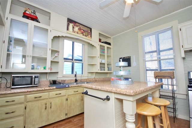 kitchen featuring sink, a kitchen breakfast bar, ceiling fan, cream cabinets, and light hardwood / wood-style flooring