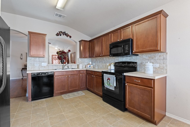 kitchen featuring vaulted ceiling, sink, backsplash, and black appliances