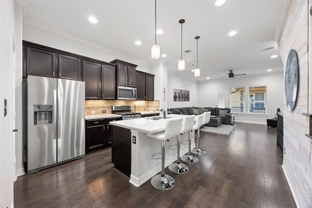 kitchen featuring sink, appliances with stainless steel finishes, a kitchen breakfast bar, pendant lighting, and a kitchen island with sink