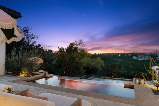 pool at dusk featuring a patio area