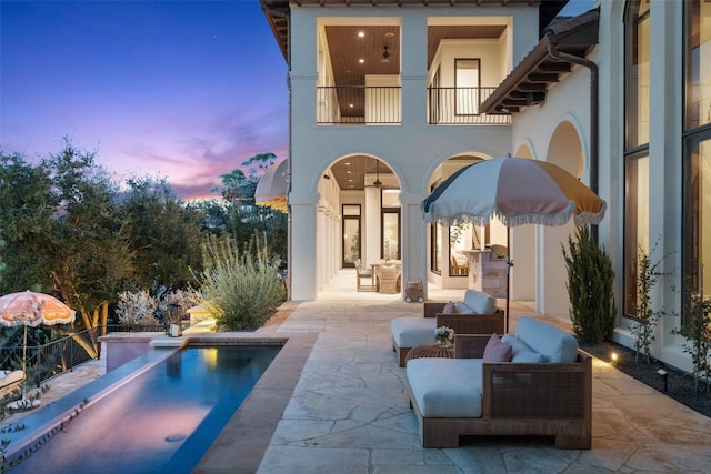 4908 Mirador Dr, Austin, TX 78735 - back of property at dusk featuring a patio area, a balcony, stucco siding, and an outdoor pool