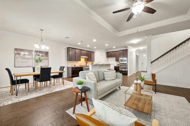 living room featuring crown molding, dark hardwood / wood-style floors, and ceiling fan with notable chandelier