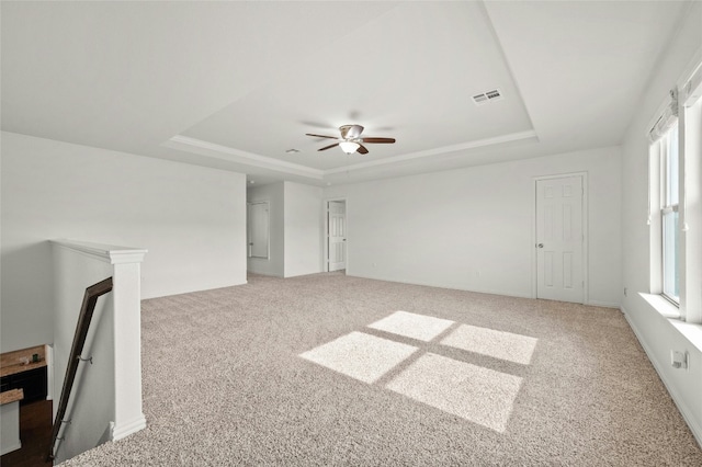 unfurnished living room with plenty of natural light, a raised ceiling, and carpet floors