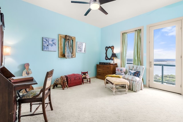 living area featuring carpet flooring, ceiling fan, and a water view