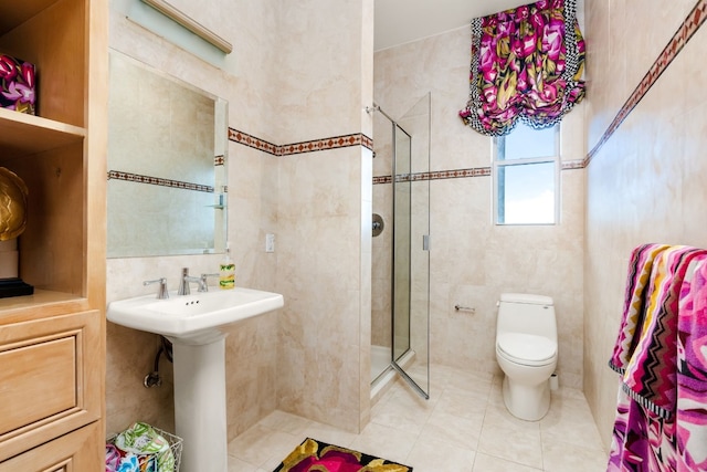 bathroom featuring toilet, a shower with shower door, sink, tile walls, and tile patterned flooring