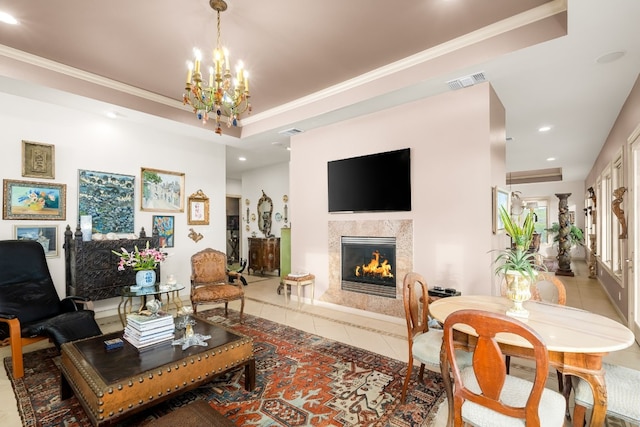 tiled living room featuring a fireplace, ornamental molding, a raised ceiling, and a chandelier