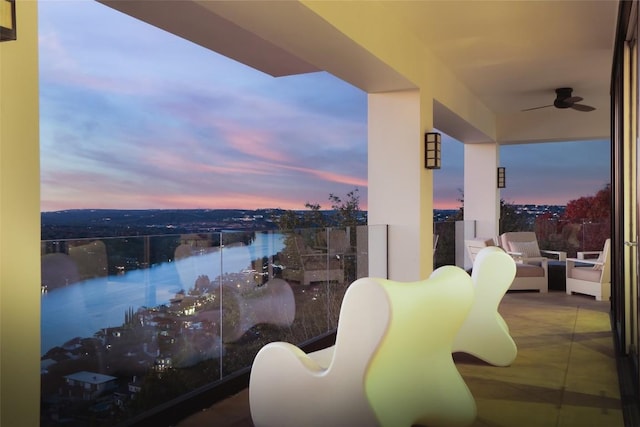 balcony at dusk featuring an outdoor living space, a water view, and ceiling fan