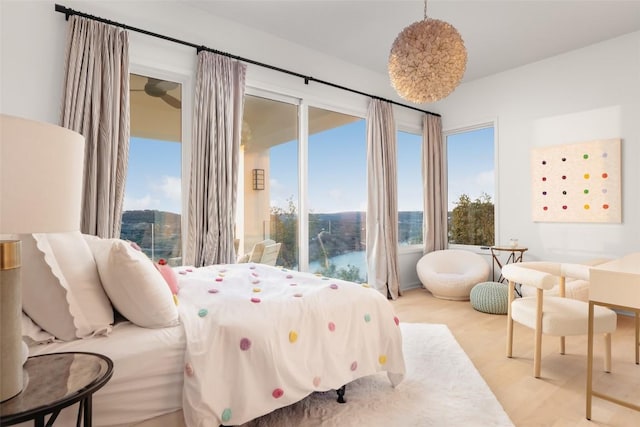 bedroom featuring a water view, access to outside, and light hardwood / wood-style flooring