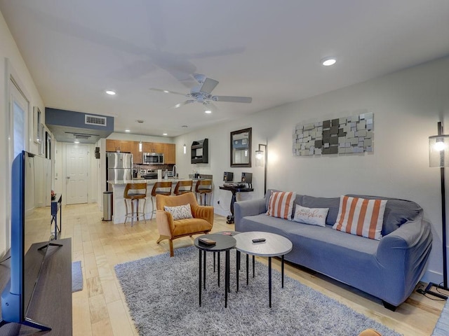 living room with sink, ceiling fan, and light hardwood / wood-style floors