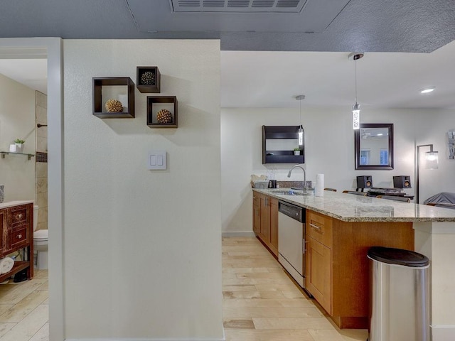 kitchen featuring light wood-type flooring, hanging light fixtures, light stone countertops, sink, and stainless steel dishwasher