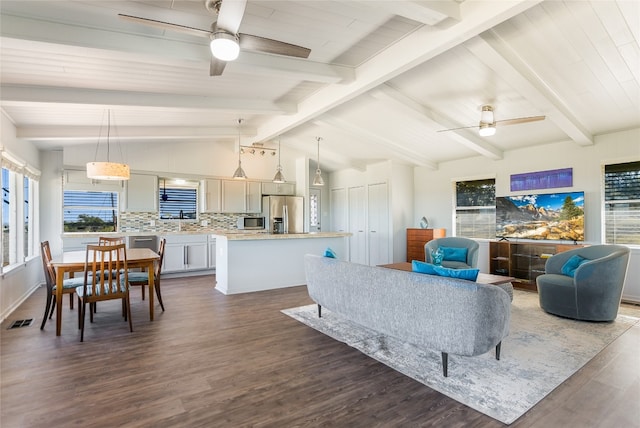 living room with ceiling fan, plenty of natural light, dark hardwood / wood-style floors, and lofted ceiling with beams