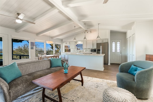 living room featuring light hardwood / wood-style flooring, lofted ceiling with beams, and ceiling fan