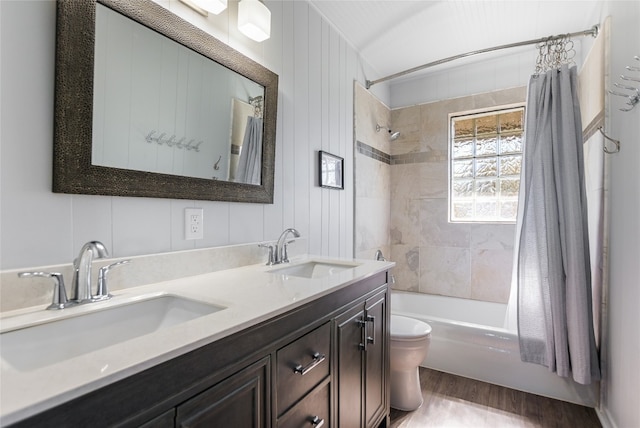 full bathroom featuring hardwood / wood-style flooring, vanity, shower / bathtub combination with curtain, and toilet