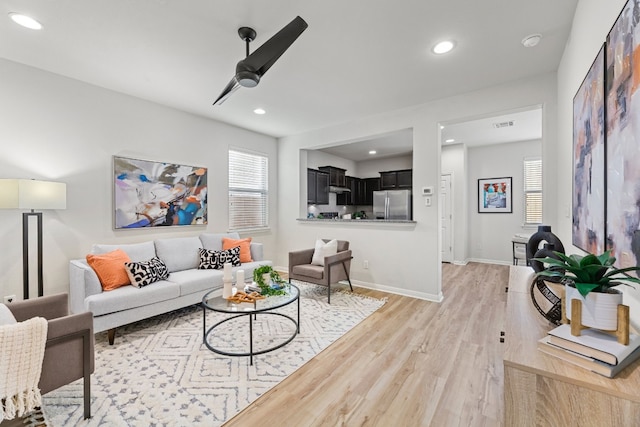 living room featuring ceiling fan, plenty of natural light, and light hardwood / wood-style floors