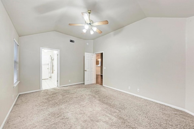 unfurnished bedroom with lofted ceiling, connected bathroom, light carpet, and ceiling fan