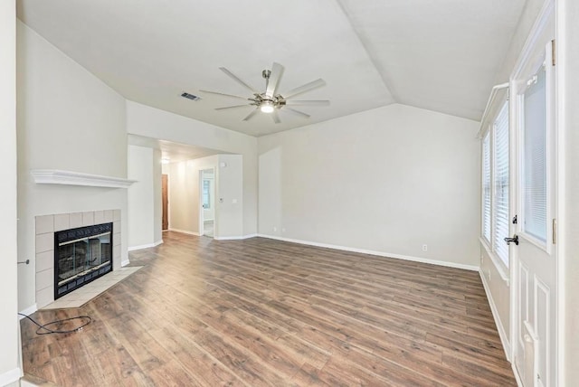 unfurnished living room with hardwood / wood-style flooring, ceiling fan, lofted ceiling, and a tiled fireplace