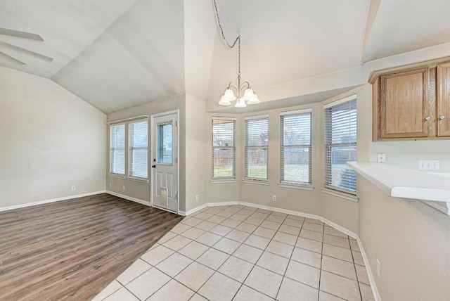 unfurnished dining area with a notable chandelier, light hardwood / wood-style floors, vaulted ceiling, and a wealth of natural light