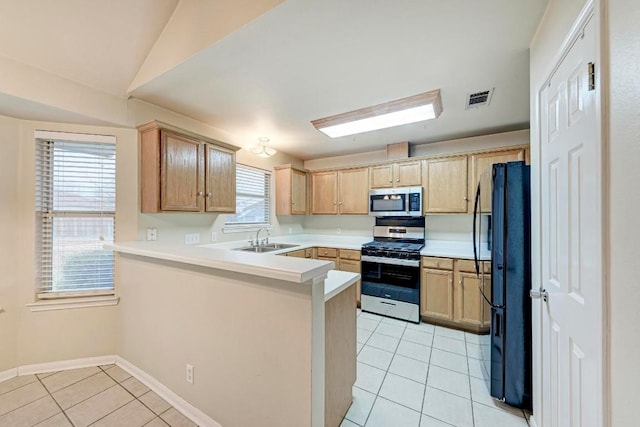 kitchen with light tile patterned flooring, stainless steel appliances, kitchen peninsula, and sink