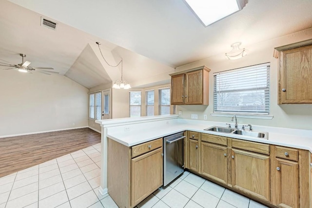 kitchen featuring vaulted ceiling, dishwasher, sink, light tile patterned floors, and kitchen peninsula