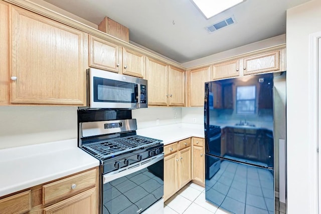 kitchen with stainless steel appliances, light tile patterned floors, and light brown cabinets