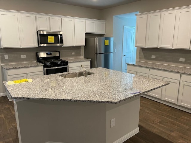 kitchen with stainless steel appliances, white cabinetry, sink, and an island with sink