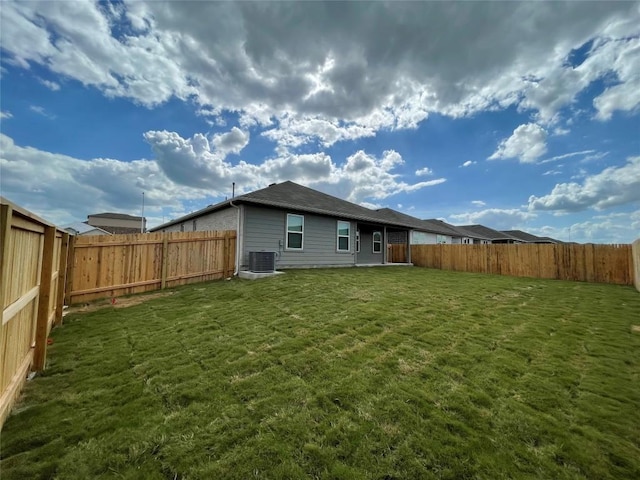 rear view of property featuring a yard and central AC