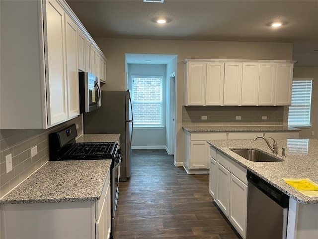 kitchen featuring stainless steel appliances, sink, white cabinets, and light stone counters