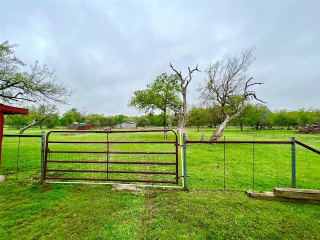 view of gate featuring a lawn and a rural view