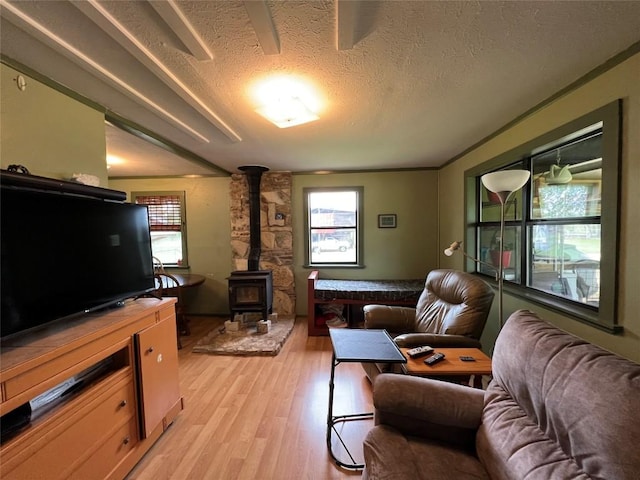 living room with a wealth of natural light, light hardwood / wood-style flooring, a textured ceiling, and a wood stove