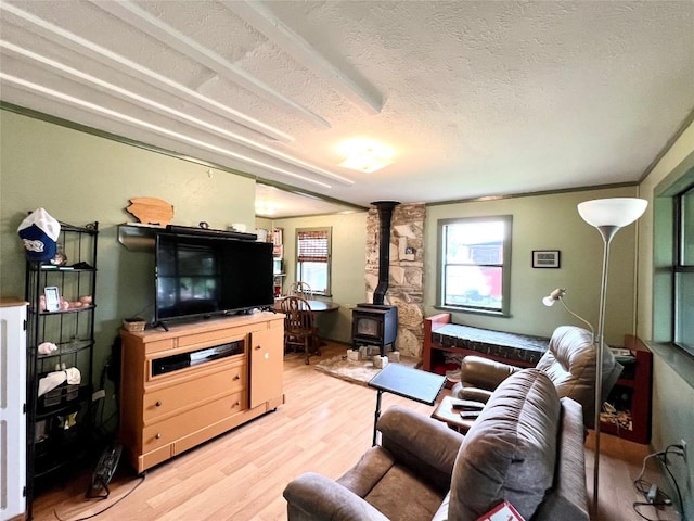 living room with a wood stove, a textured ceiling, and light hardwood / wood-style floors