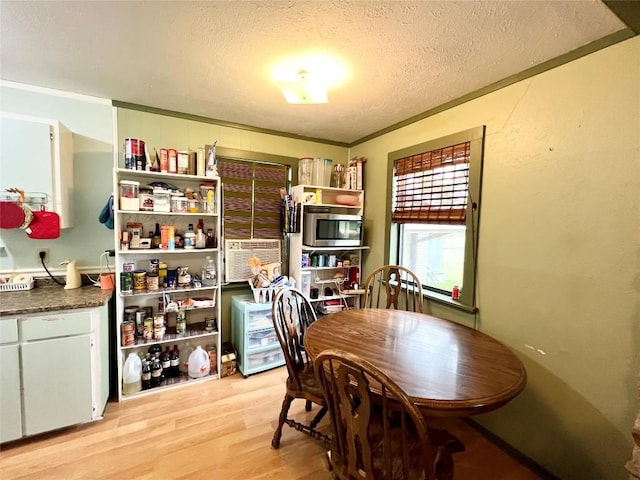 dining area with ornamental molding, a textured ceiling, and light wood-type flooring