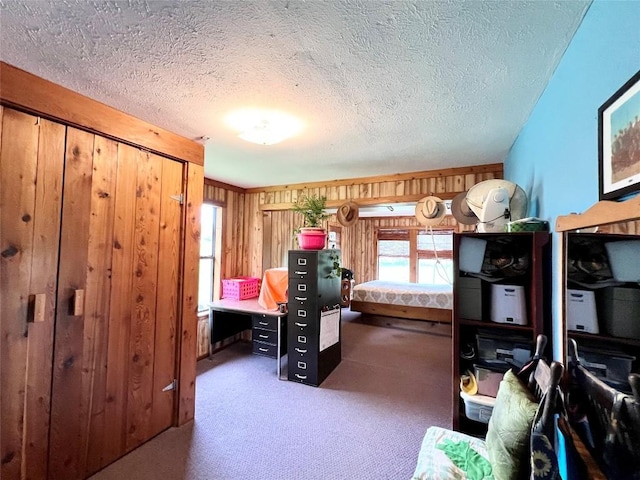 carpeted bedroom featuring a textured ceiling and wooden walls