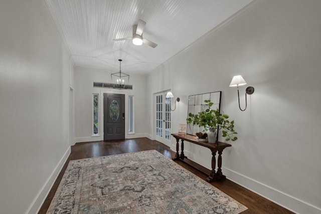 foyer entrance with crown molding, dark wood-type flooring, and ceiling fan with notable chandelier