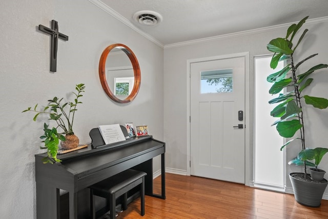 entrance foyer with ornamental molding and hardwood / wood-style floors